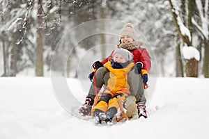 Little boy and mother sliding in the park during a snowfall