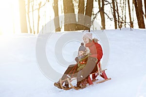 Little boy and mother sliding in the park during a snowfall