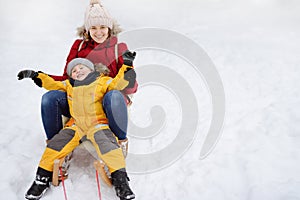 Little boy and mother sliding in the snow