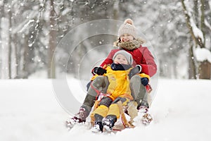 Little boy and mother sliding in the snow