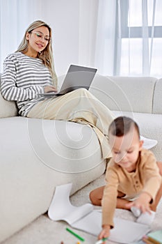 Little boy and mother spending weekends at home together, child drawing on floor