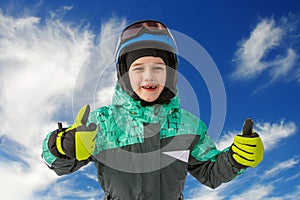 Little boy on mountains in ski helmet with fallen first tooth