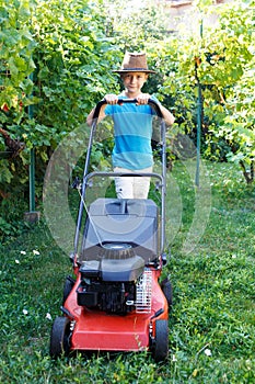 Little boy mowing lawn in backyard