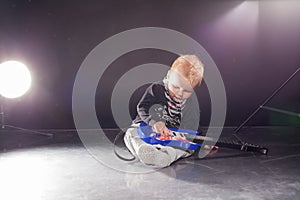 Little boy musician playing rock music on the guitar