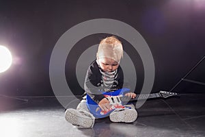 Little boy musician playing rock music on the guitar