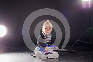 Little boy musician playing rock music on the guitar