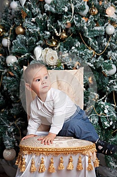 Little boy near fir tree with Christmas gift. Indoor