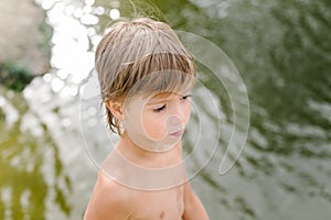 Little boy near water at the beach on hot summer day