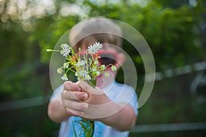 Little boy not in focus holding the flovers presenting the flowers