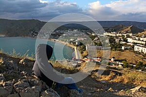 Little boy observing sea and city from the hill