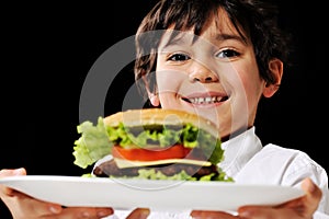 Little boy offering a hamburger on plate