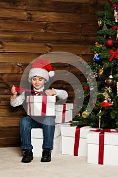 Little boy opening gift box under christmas tree