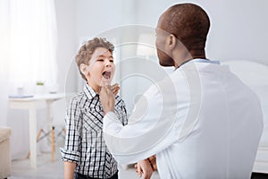 Little boy opening mouth for male doctor