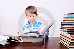 Little boy opens a large book and looking into it