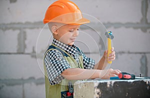 Little boy in orange protective helmet with instruments for renovation. Repair home.