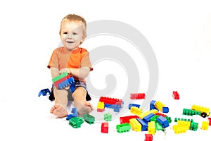 Little boy in an orange shirt is played Lego photo