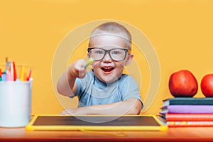 Little boy painting and doing homeworks on his desk having an idea, inspiration concept. back to school on yellow background