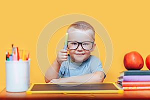 Little boy painting and doing homeworks on his desk having an idea, inspiration concept. back to school on yellow background