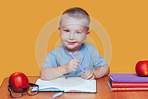 Little boy painting and doing homeworks on his desk, inspiration concept. back to school on yellow background