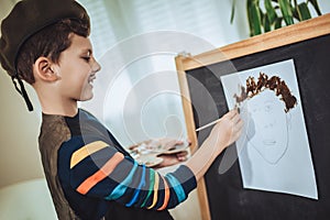 Little boy painting a picture in home studio