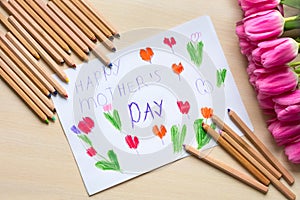 Little boy paints greeting card for Mom on Mother`s Day with the inscription `Happy mother`s day`