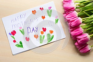 Little boy paints greeting card for Mom on Mother`s Day with the inscription `Happy mother`s day`.