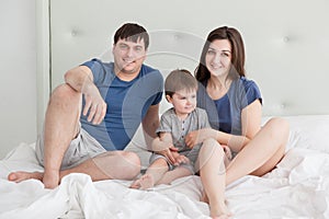 Little boy and parents On Parents Bed Wearing Pajamas