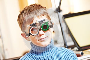 Little boy with phoropter at ophthalmology clinic