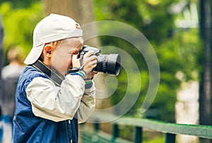 Little boy with photo camera makes a shoot