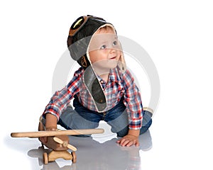A little boy in a pilot`s cap and a wooden plane in his hand