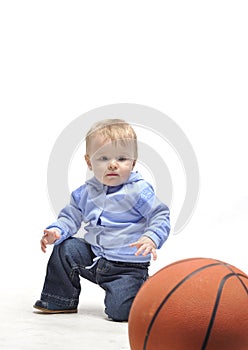 Little boy plaing with basketball ball in studio