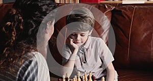 Little boy play chess board game with mom