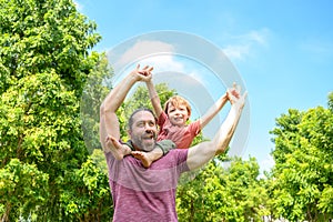 little boy play with dad on summer day. father carries his son on his shoulders in park. father day happy family child dream