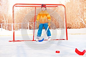 Little boy play ice hockey outside on winter day