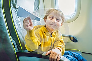 Little boy play with paper plane in the commercial jet airplane flying on vacation