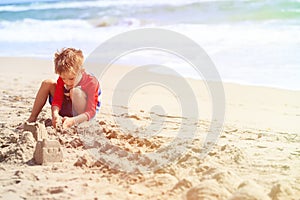 Little boy play with sand on summer beach