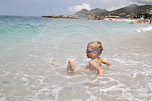 little boy play with splahes waves of the sea