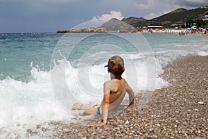 little boy play with splahes waves of the sea