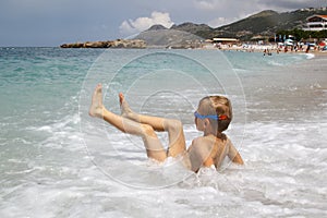 little boy play with splahes waves of the sea