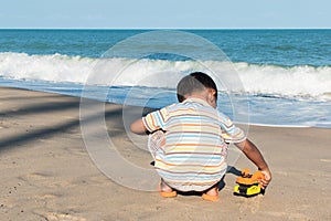 little boy play toy car on the beach