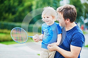 Little boy playing badminton with dad on the playground