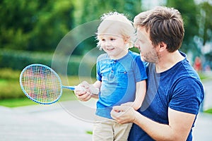 Little boy playing badminton with dad on the playground