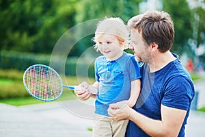 Little boy playing badminton with dad on the playground