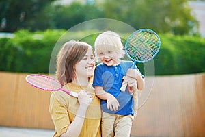 Little boy playing badminton with mom on the playground