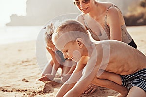 Little boy playing on the beach sand with his family