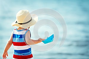 Little boy playing at the beach in straw hat