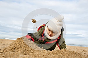 Little boy playing on beach in winter