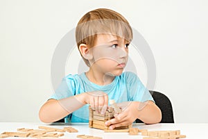 Little boy playing with building blocks on a table. Kid building wooden house