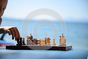 Little boy playing chess on the beach