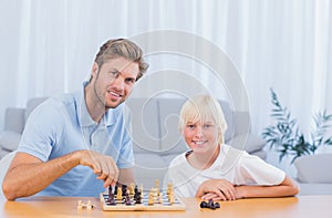 Little boy playing chess with his father